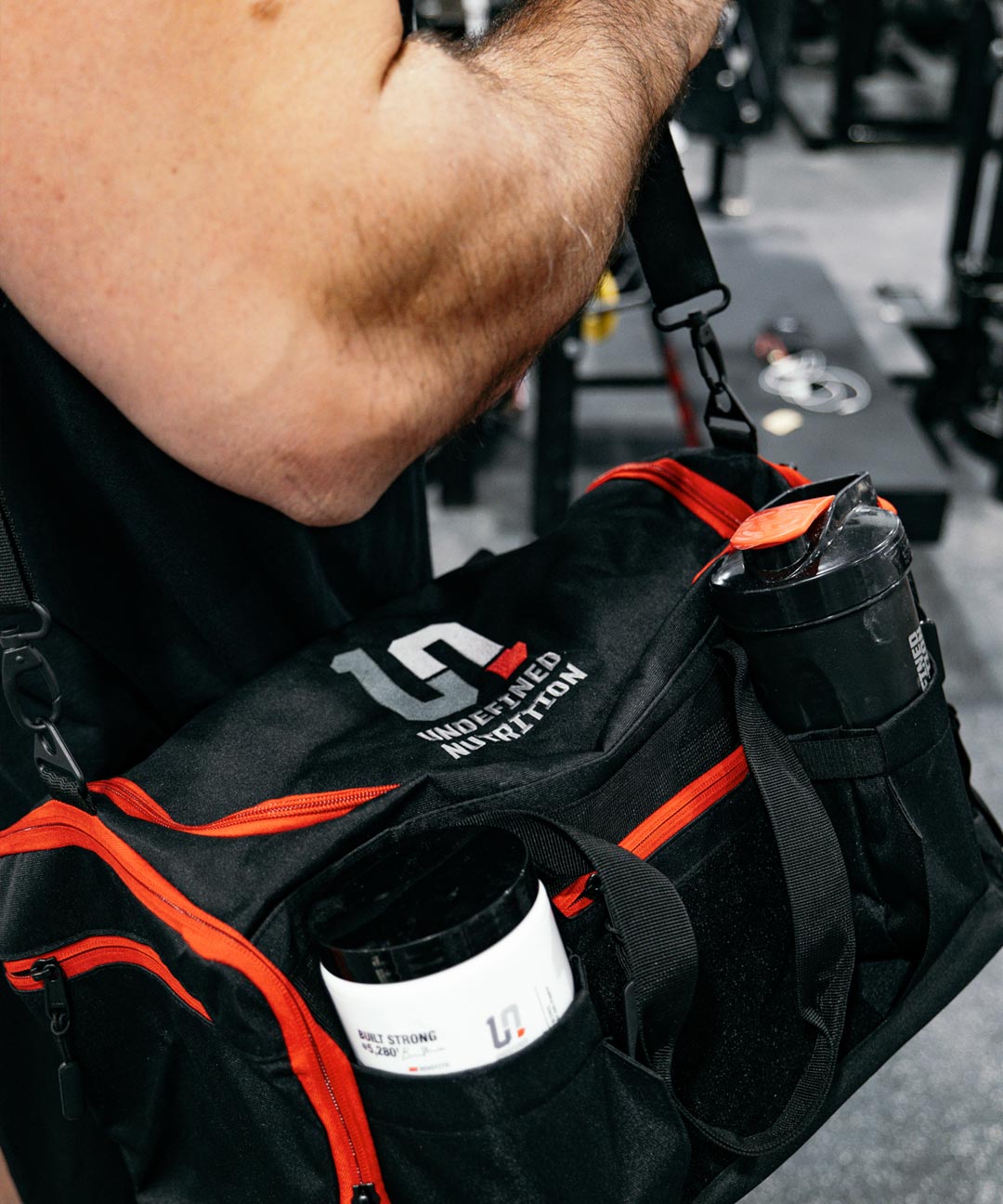 Brian Shaw with black and red gym bag with Undefined Nutrition branding.