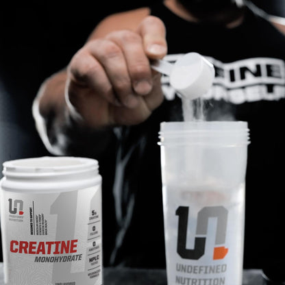 Person pouring powder from a container labeled 'Undefined Nutrition' into a clear container.