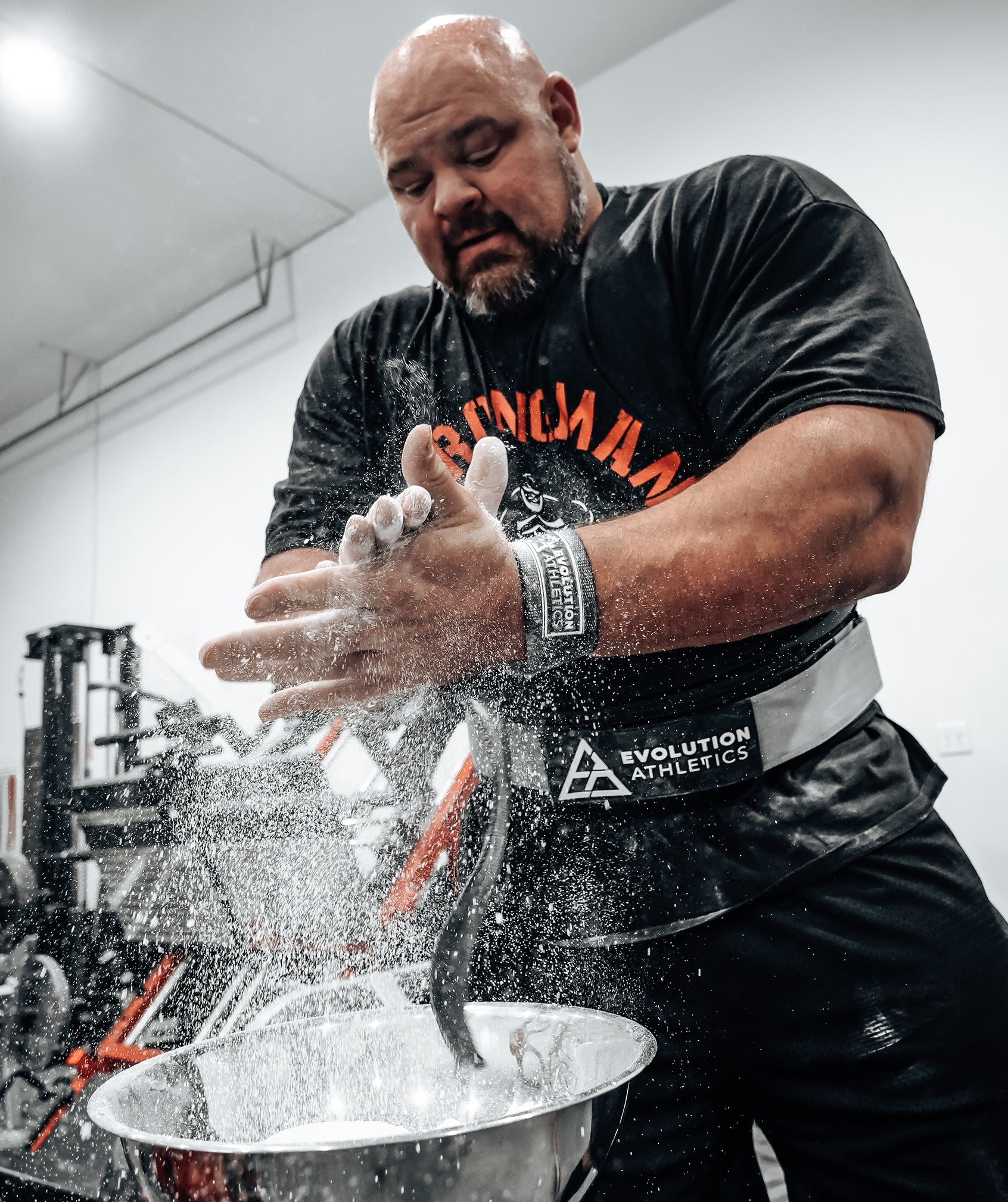 Brian Shaw in a gym setting applying chalk to his hands
