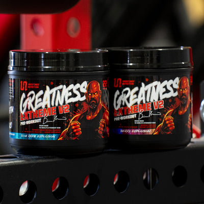 Two black tubs of Undefined Nutrition Greatness V2 Extreme Pre-Workout powder on a black metal shelf in a gym setting.