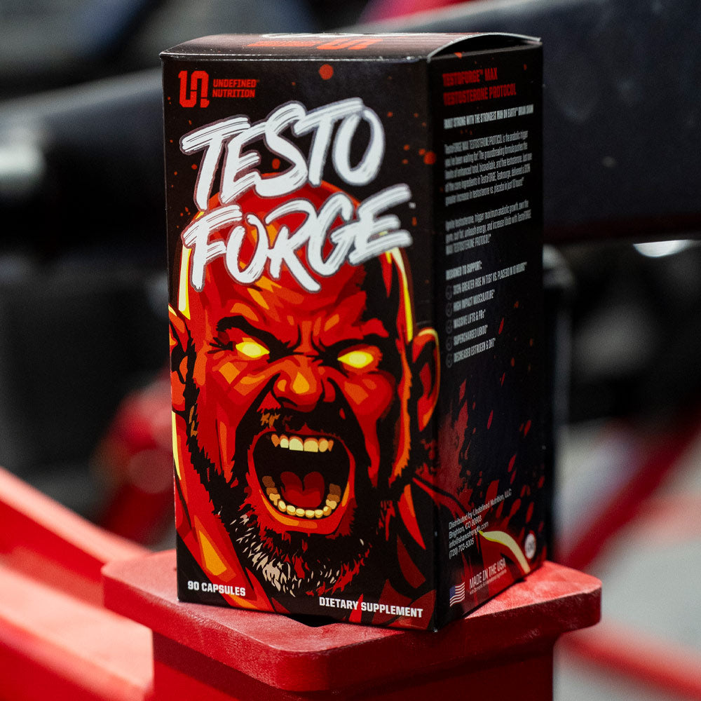 A box of TestoFORGE dietary supplement, featuring an illustration of Brian Shaw on a black background, displayed on a red stand.